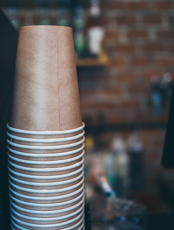 Stack of small brown paper cups made of craft paper prepared for coffee, tea or water in loft style  cafe background with copy space.の写真素材