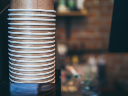 Stack of small brown paper cups made of craft paper prepared for coffee, tea or water in loft style  cafe background with copy space.の写真素材