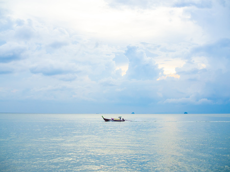 Boat driver on traditional long tail boat in the sea with cloud and blue sky background in Thailand...