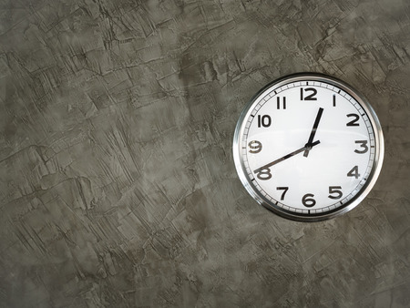 White steel round shape clock on grey concrete wall with copy space.の写真素材