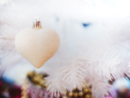 Christmas ornament decoration background. Christmas glitter white heart hanging on white Christmas tree with copy space.の写真素材