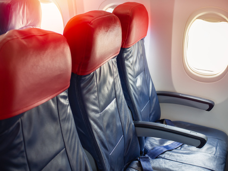 Empty passenger airplane seats near the window in the cabin of low cost commercial airplane. Dark blue and red leather seats in economy class.の写真素材