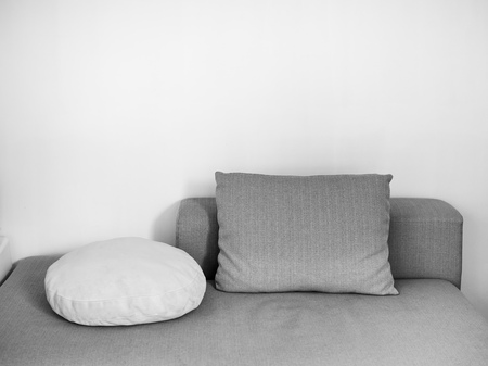 White and gray pillows on sofa on white wall background in cozy living room with copy space.の写真素材