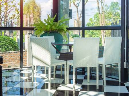 White weave chairs and brown weave table in restaurant. Modern dining table set on black and white...