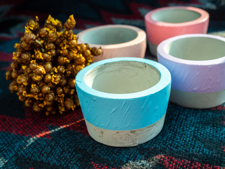 Colorful round geometric d concrete planters with flowers on fabric background. Modern beautiful...