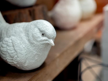 Close-up white realistic mortar bird sculpture decoration on wooden background.の写真素材