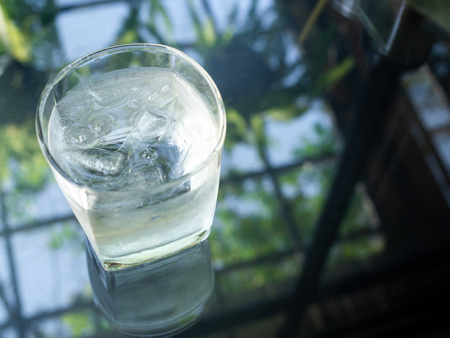 A glass of cold drinking water with ice on glass table with copy space on top view.の写真素材