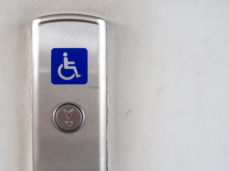 Elevator button with blue disabled people sign on stainless steel elevator panel on old and dirty...