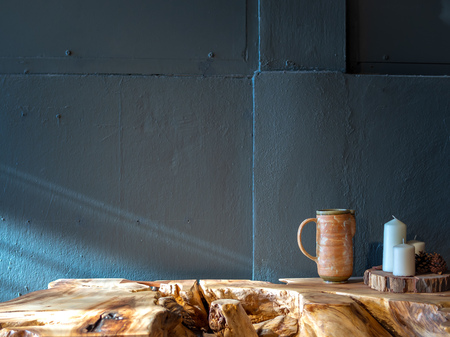 Ceramic mug with white wax candles decoration on wood table on blue painted concrete wall background with copy space.の写真素材