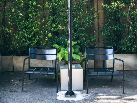 Two black chairs in smoking area on green tree background.の写真素材