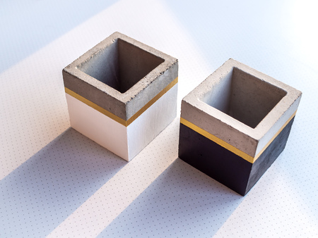 Two empty modern black and white cubic concrete planters on white background. Painted concrete pot for home decoration.の写真素材