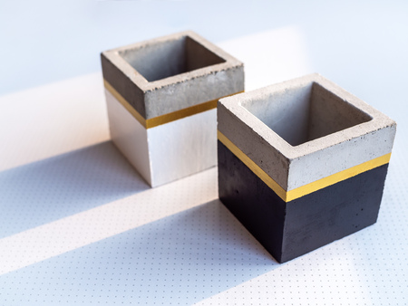 Two empty modern black and white cubic concrete planters on white background with copy space. Painted concrete pot for home decoration.の写真素材