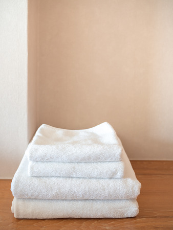 White clean towels on wooden surface and white wall background with copy space vertical style.の写真素材