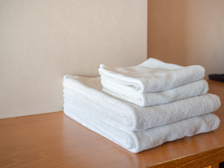 White clean towels on wooden surface and white wall background with copy space.の写真素材