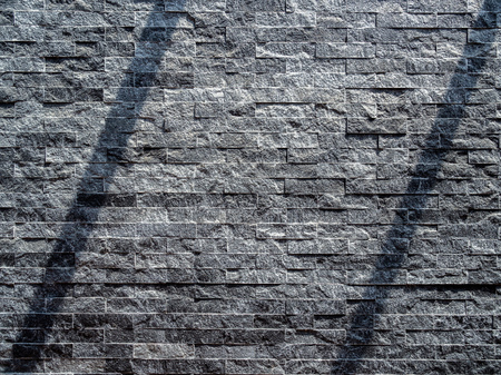 Modern grey brick wall texture background. Shadow shade light on stone brick tiles texture. Minimalist style wall background with copy space.の写真素材