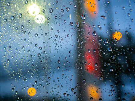Close-up rain drops texture on car window with colorful bokeh abstract background.の写真素材
