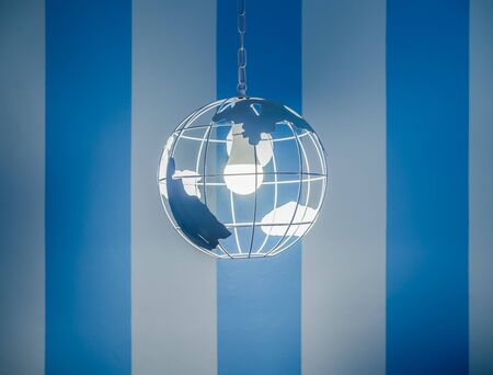 Modern global earth world shape ceiling lamp on white and blue striped wall background.の写真素材