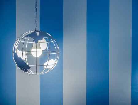 Modern global earth world shape ceiling lamp on white and blue striped wall background with copy space.の写真素材