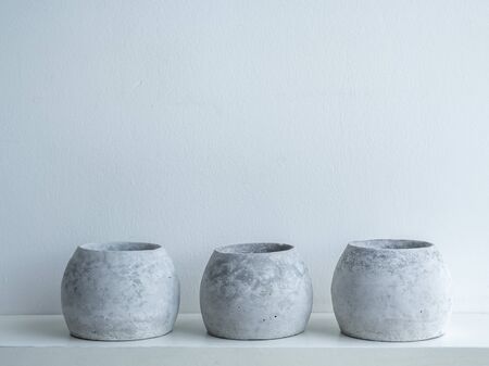 Concrete pots. Empty three modern round concrete planters on wooden shelf isolated on white...