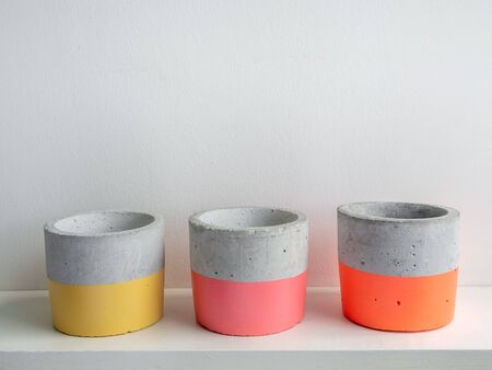 Empty colorful modern geometric concrete planters on white shelf isolated on white background. Beautiful painted concrete pots.の写真素材