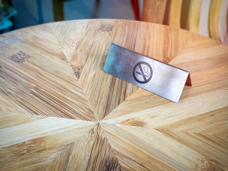 No smoking sign on wooden table. Warning sign, no smoking icon on silver metallic style plate sign.の写真素材