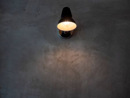 Modern wall lamp on concrete wall shining in the dark with copy space.の写真素材