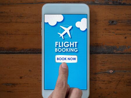 Flight booking online with smartphone. Top view finger touching on mobile phone for buying or booking air flight online airline ticket.の写真素材
