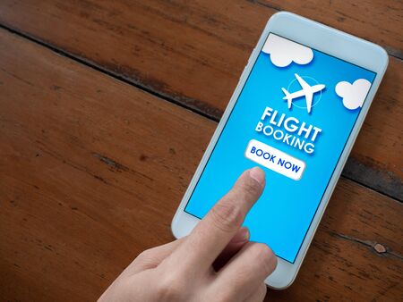 Flight booking online with smartphone. Top view finger touching on mobile phone for buying or booking air flight online airline ticket with copy space.の写真素材