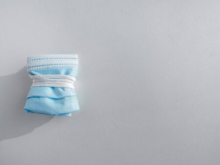 Used mask concept. Folded used protective face mask isolated on white background with copy space. Protection before littering for prevent spread of virus.の写真素材