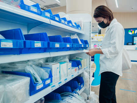 Bangkok, Thailand - March 25, 2020: Asian woman wearing protective face mask looking medical productin pharmacy store in Bangkok, Thailand.のeditorial素材