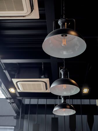 Three black round modern ceiling lights and cassette type air conditioner inside the cafe loft style, vertical style.の写真素材