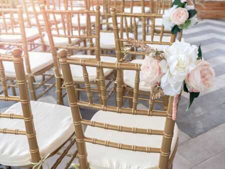 Wedding chairs decorate with beautiful flowers for wedding ceremony. Wedding set up with golden chairs.の写真素材