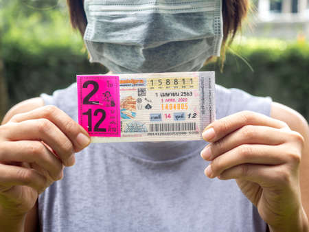 Bangkok, Thailand - April 14, 2020: Hand holding Thai Lottery for the period April 1, 2020. Thai national lottery scheduled for April 1 will now take place on May 2, and may be postponed because the effects of Covid-19 coronavirus pandemic.のeditorial素材