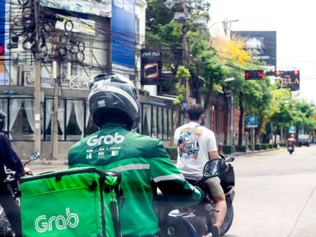 Bangkok, Thailand - April 18, 2020: Grab Food Delivery, Man with delivery container with motorcycle for food delivery on the road by Grab, famous application on smartphone.のeditorial素材