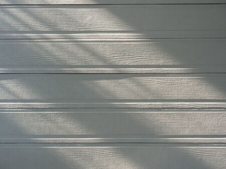 Soft white empty wooden surface background. Warm light and shadow on wood plank texture.の写真素材