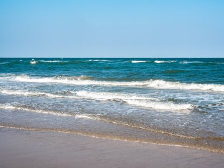 Seascape, sea waves breaking on the shore with clean beach on blue sky background.の写真素材