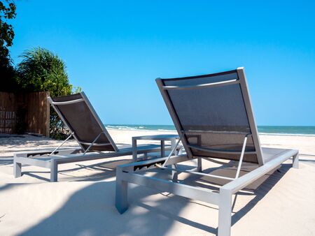 Empty wooden sunbed on sand beach on blue sky background.の写真素材