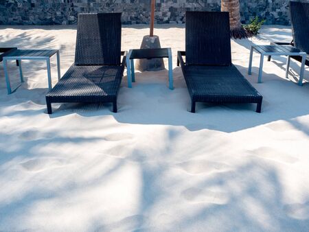Empty wooden sunbed on sand beach background with copy space.