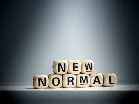 Spotlight shines on New Normal, words on wooden alphabet cube on dark background. New normal after...