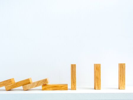 Social Distancing concept. Row of falling and standing wooden dominoes with distance space on shelf on white background with copy space.の写真素材