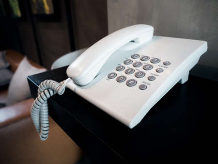 White landline phone. landline telephone for residential internal calls only on black shelf in modern condo.の写真素材
