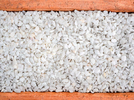 White pebble background. Stone gravel texture in terracotta pot, top view.
