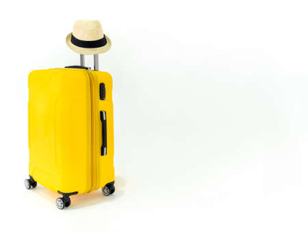 Yellow suitcase with straw hat on isolated on white background with copy space. Large yellow luggage or travel bag on wheels with straw hat on metal long handle, summer holiday traveling concept.の写真素材