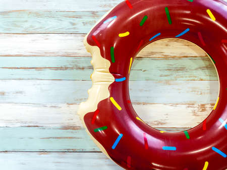 Beach accessories, brown donut shaped swim ring on vintage wooden plank with space. Travel and vacation summer holiday background, top view.の写真素材