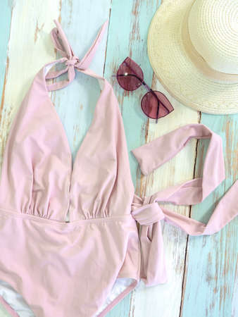 Beach accessories, vintage pink women swimwear with sunglasses retro style and straw hat on wooden plank, vertical style. Travel and vacation summer holiday background, top view.の写真素材