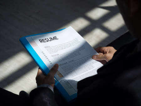 Resume documents or curriculum vitae paper in hands of a unemployed man applicant in a suit sitting...