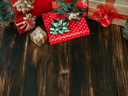 Christmas and happy new year background. Beautiful many size of red and gold gift box with shiny green, red and gold bow decorations on dark wooden plank background with copy space.の写真素材