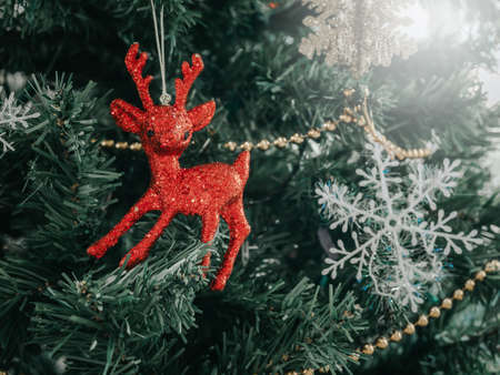 Close-up cute red reindeer with snowflake ornament on Christmas tree background. Close-up Christmas...