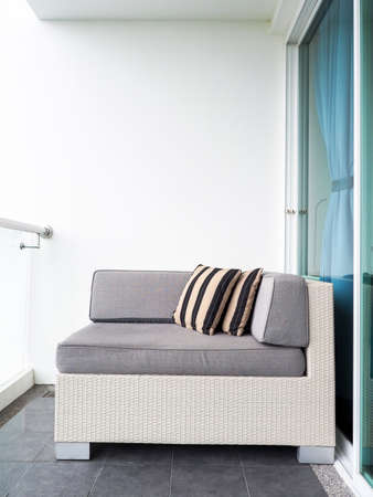 Comfortable rattan sofa bed with pillows decorated on balcony and patio on high building on white...