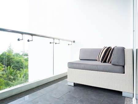 Comfortable rattan sofa bed with pillows decorated on balcony and patio on high building on white...